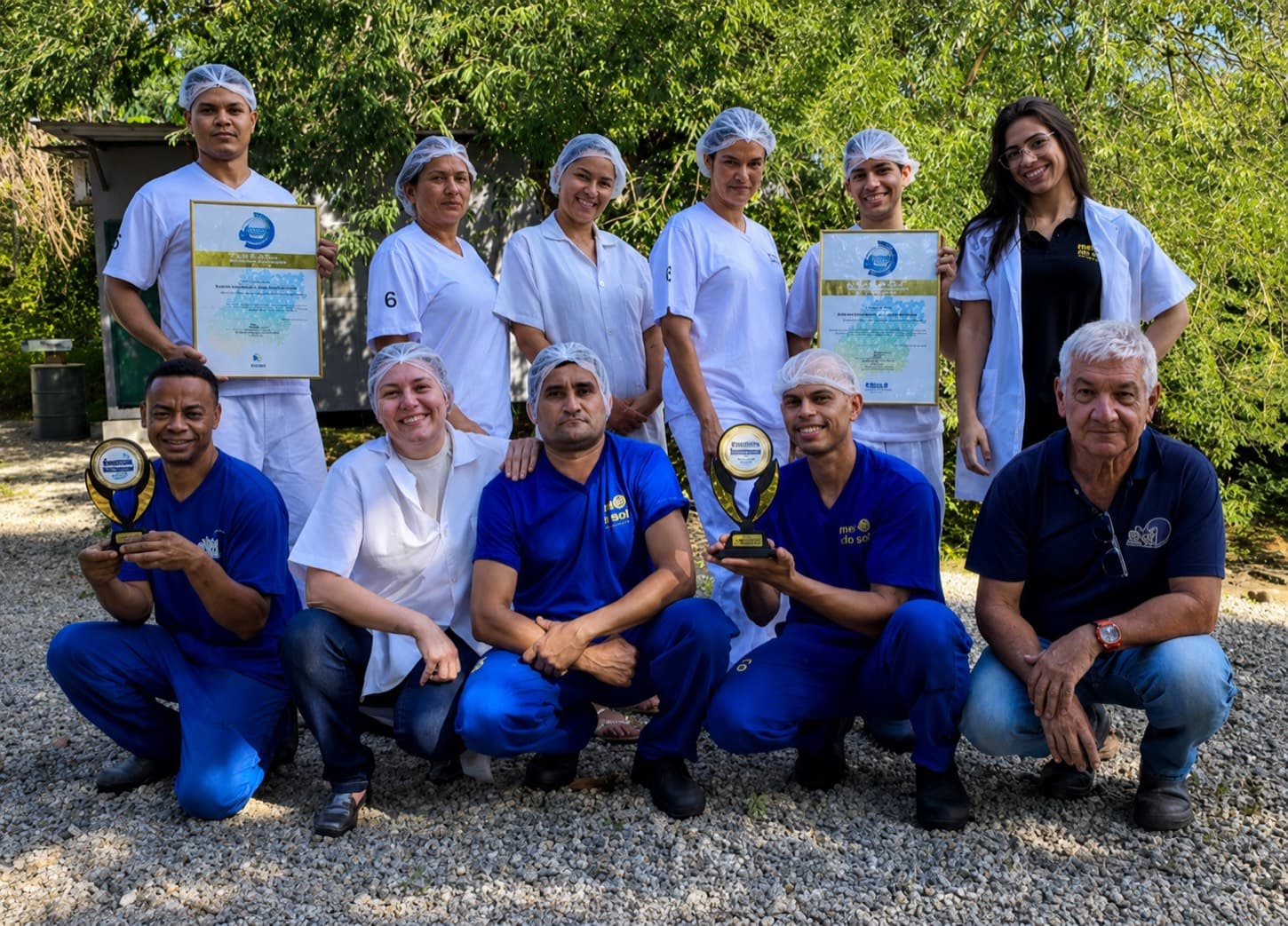 Equipe da fábrica reunida segurando prêmios e certificados de qualidade